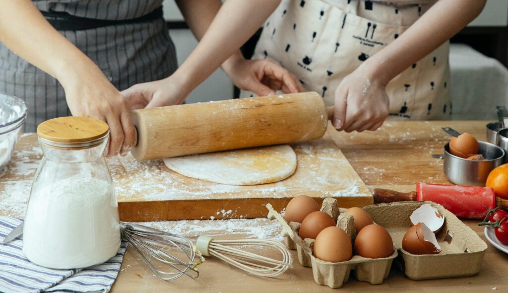 women making dough on chopping board on table