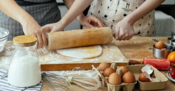 women making dough on chopping board on table